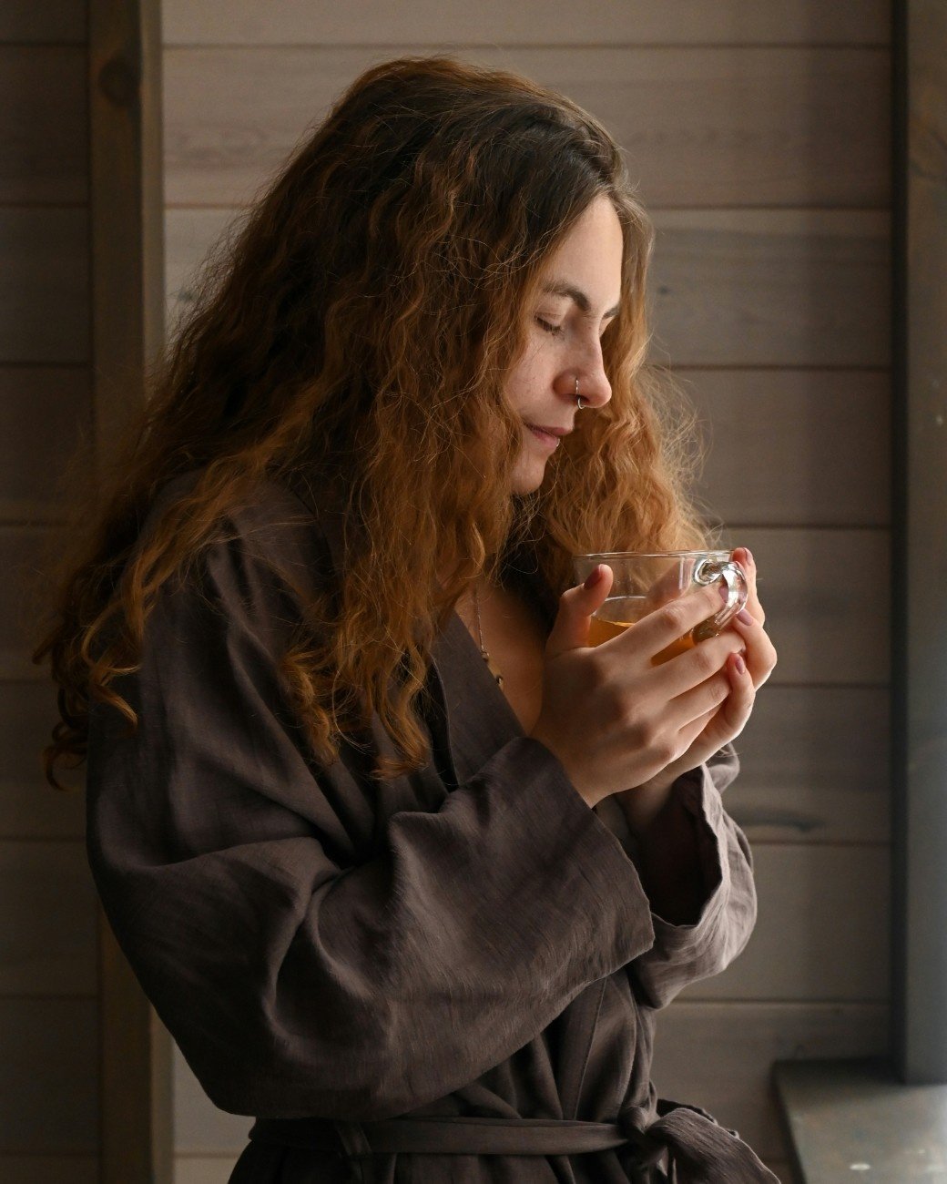 Woman sitting by window holding coffee in hand