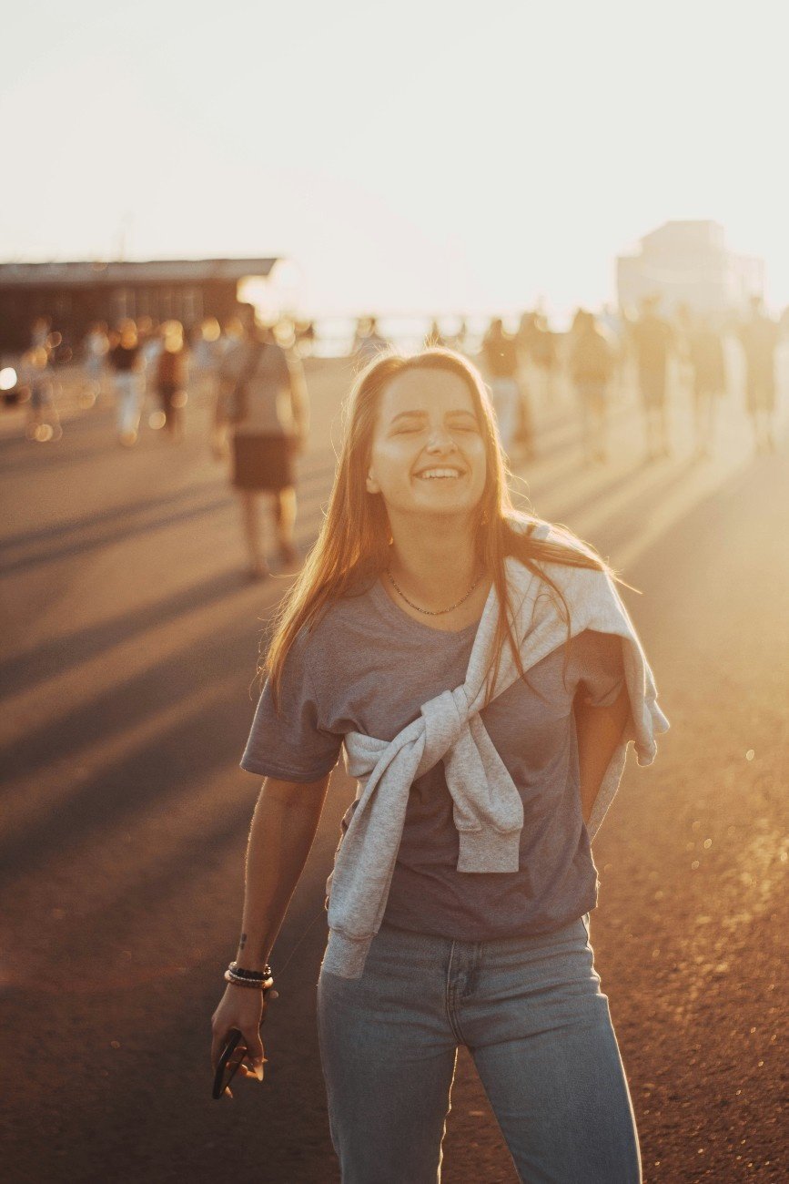 Woman walking in warm sunlight, looking peaceful and free.