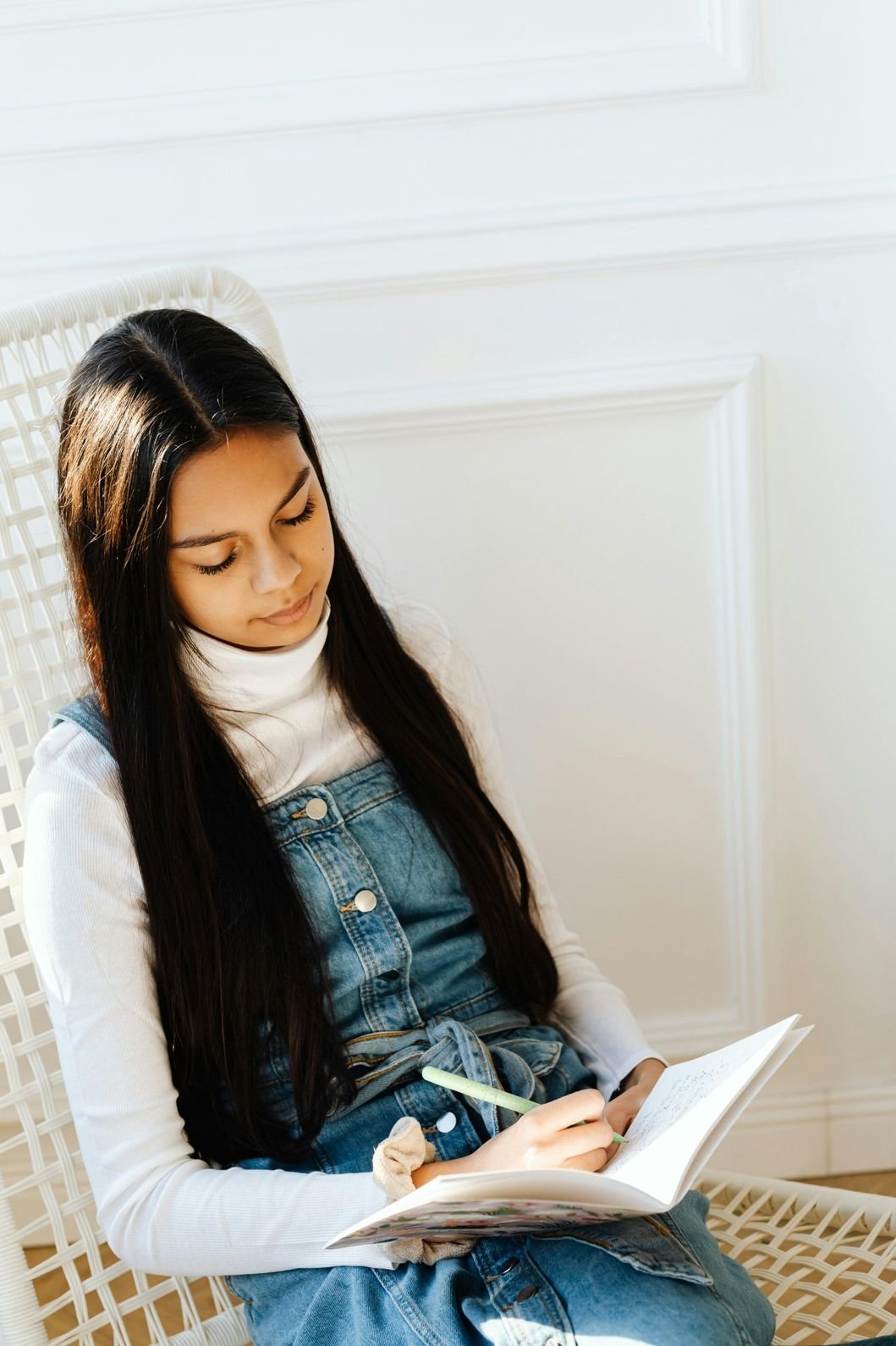 Woman journaling peacefully by the window in sunlight.