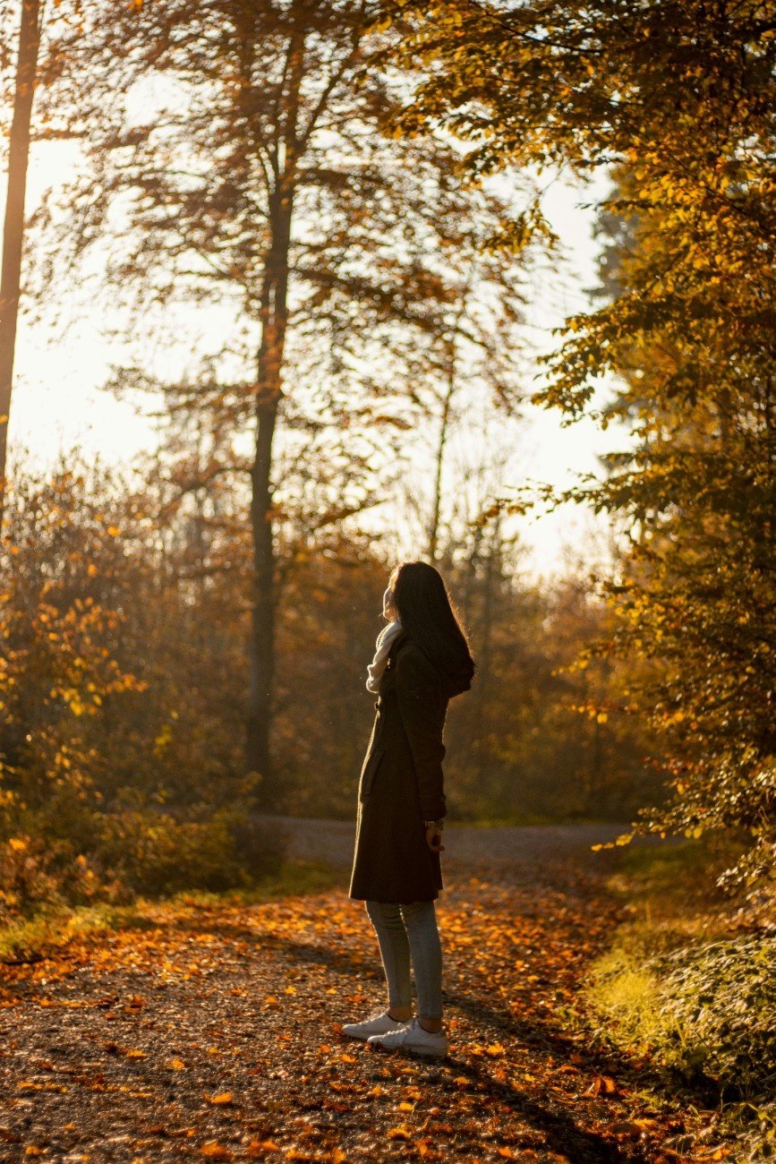 Woman walking into sunrise, free and peaceful.