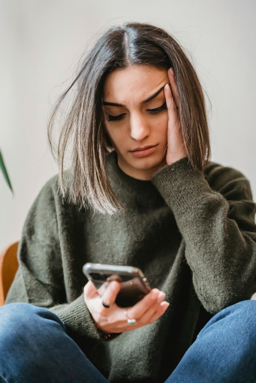 woman holding phone sitting bed
