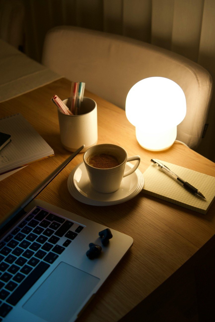 woman working calmly at night with coffee beside laptop, symbolizing patience in side hustle.